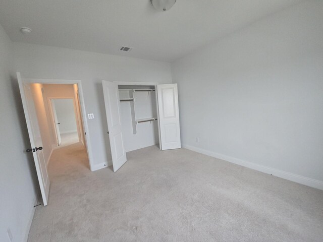 unfurnished bedroom with light colored carpet, baseboards, and a closet