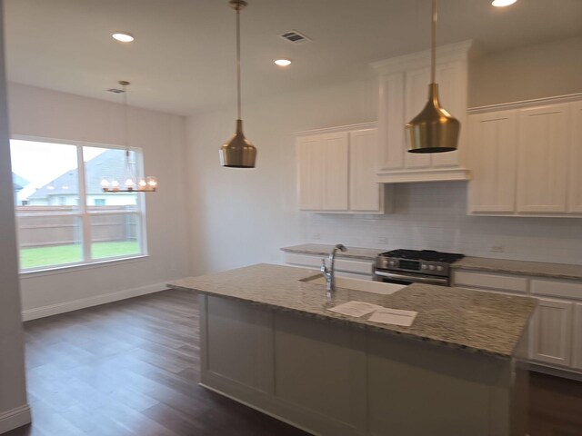 kitchen with stainless steel gas range oven, a sink, decorative backsplash, light stone counters, and white cabinetry