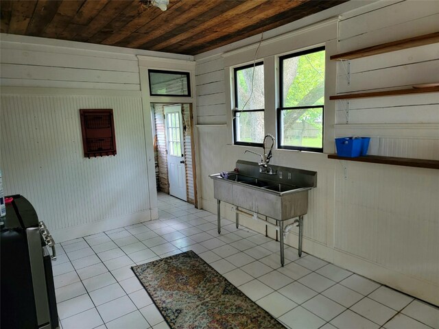 1208 W Broadway, Clarksville, TX 75426 - kitchen with wooden ceiling, tile patterned floors, wood walls, baseboards, and a sink