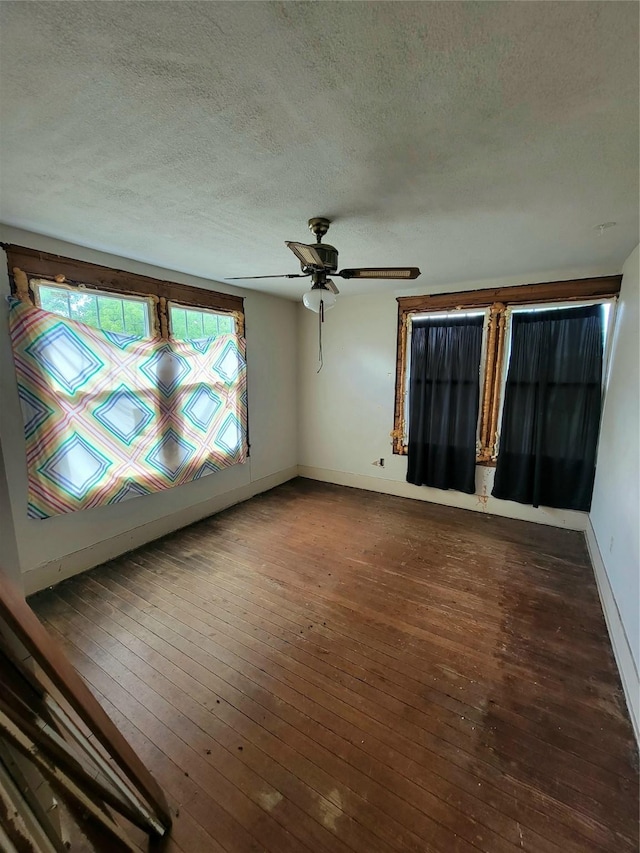 1208 W Broadway, Clarksville, TX 75426 - empty room featuring a textured ceiling, wood-type flooring, baseboards, and a ceiling fan