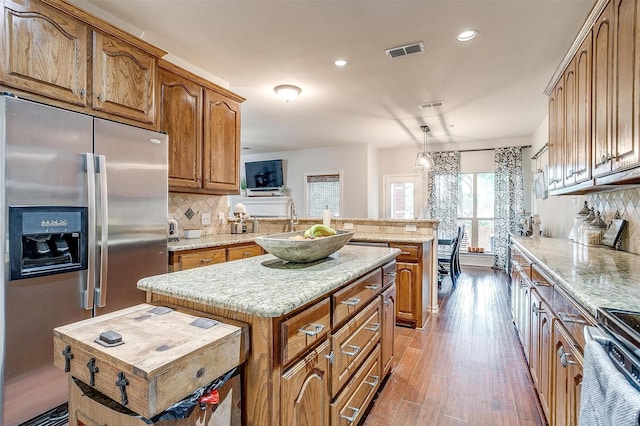 558 Ascot Way, Azle, TX 76020 - kitchen featuring stainless steel refrigerator with ice dispenser, a kitchen island, brown cabinetry, decorative backsplash, and recessed lighting