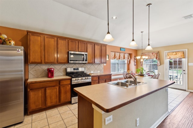2377 Sunshine Dr, Little Elm, TX 75068 - kitchen with stainless steel appliances, a sink, brown cabinetry, and decorative backsplash