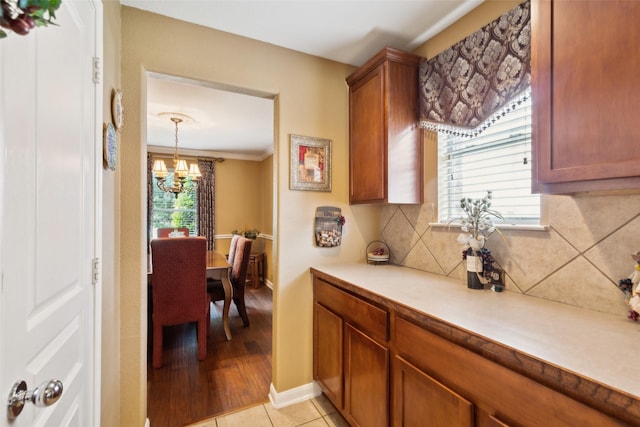 2377 Sunshine Dr, Little Elm, TX 75068 - kitchen featuring a chandelier, tasteful backsplash, light countertops, brown cabinets, and crown molding