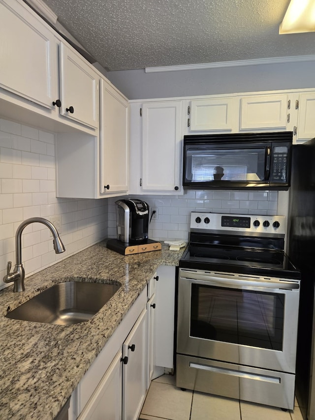 kitchen with black microwave, stainless steel electric range, a sink, white cabinets, and light stone counters