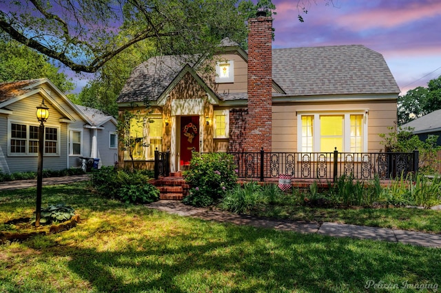 bungalow-style home featuring a lawn, a chimney, and a shingled roof