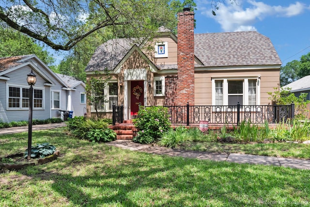 view of front facade featuring a front lawn, a chimney, roof with shingles, and a deck