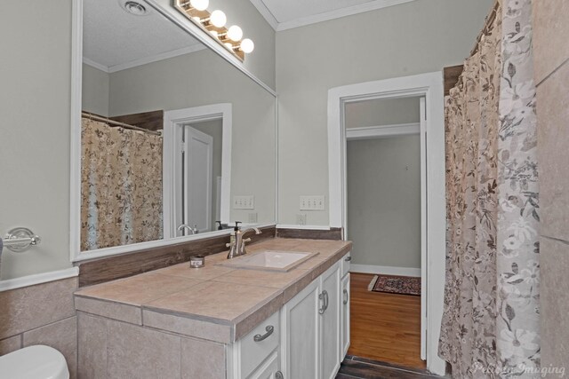 bathroom featuring crown molding, wood finished floors, vanity, and toilet