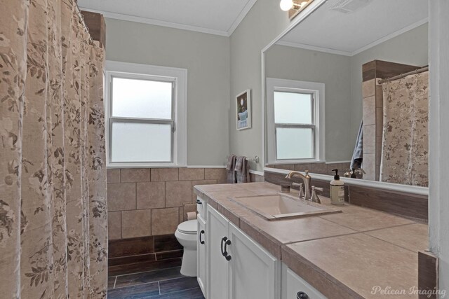 bathroom featuring tile walls, toilet, a wainscoted wall, crown molding, and vanity