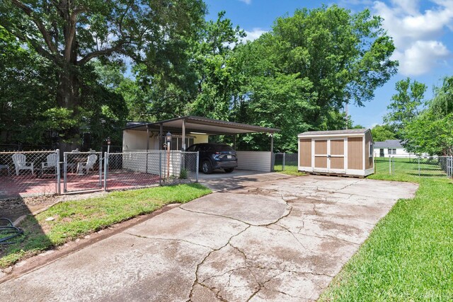 view of patio with a storage shed, an outbuilding, driveway, a gate, and a carport
