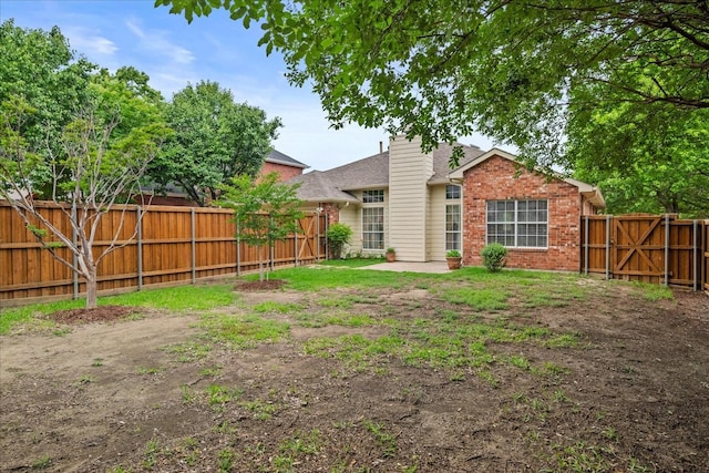 2617 Jacques Ln, Mckinney, TX 75070 - rear view of property with a fenced backyard, brick siding, and a chimney