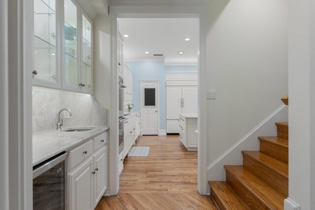 indoor wet bar with wine cooler, light wood-type flooring, stairs, backsplash, and recessed lighting