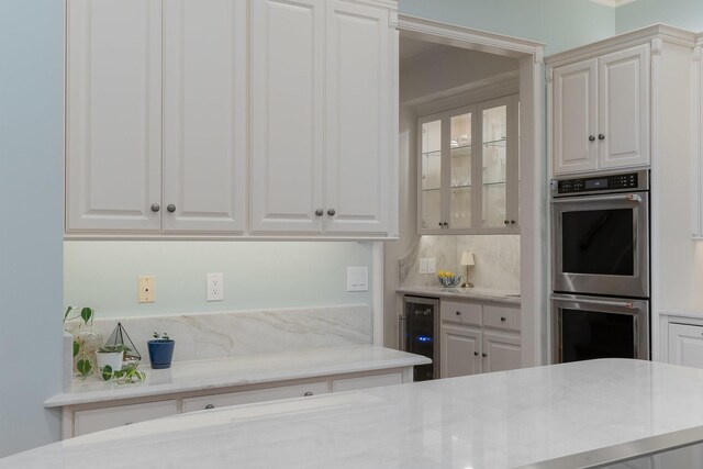 kitchen featuring stainless steel double oven, wine cooler, and white cabinets