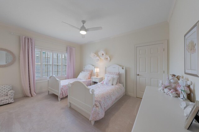 bedroom featuring crown molding, light colored carpet, baseboards, and a ceiling fan