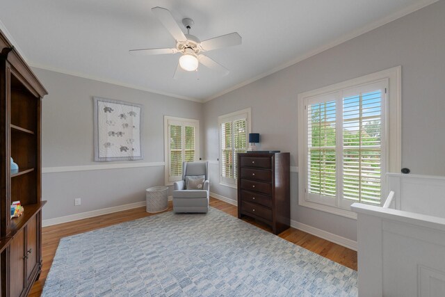 living area featuring wood finished floors, ornamental molding, a ceiling fan, and baseboards