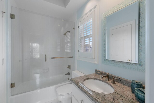 bathroom with toilet, vanity, and combined bath / shower with glass door