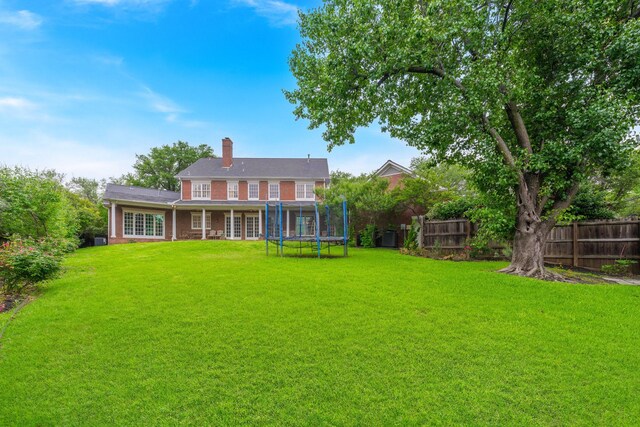 rear view of house featuring a trampoline and a chimney