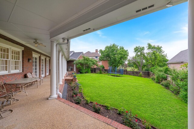 view of yard featuring a trampoline, ceiling fan, and a patio area