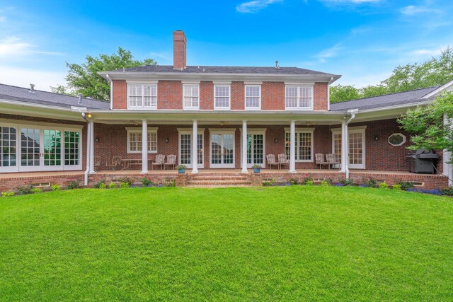 rear view of property with a lawn, a chimney, and brick siding