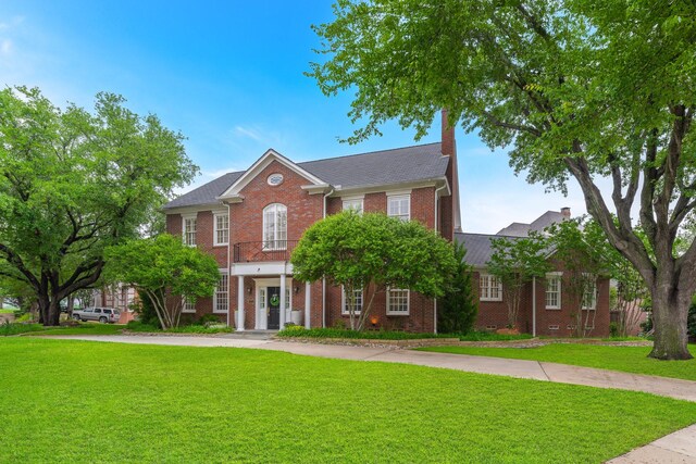 view of front facade with brick siding and a front yard