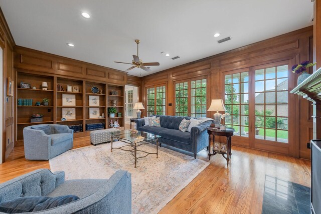 living room featuring ceiling fan, light wood-style floors, recessed lighting, and wooden walls