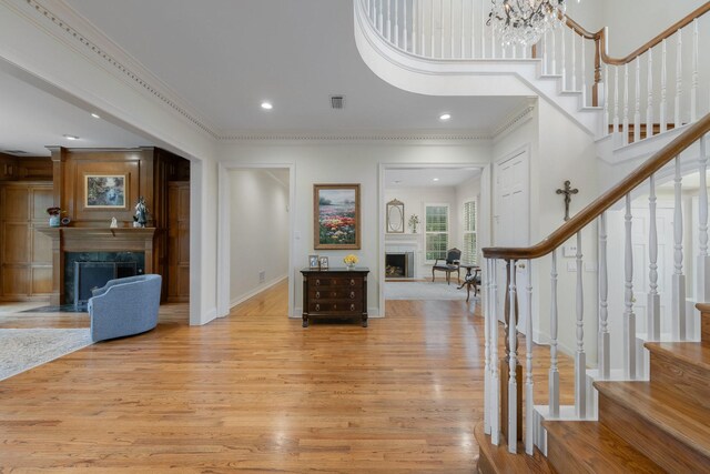 entryway featuring a premium fireplace, light wood-style floors, stairway, ornamental molding, and baseboards