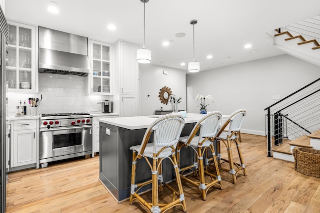 3420 Rosedale Ave Unit 6, University Park, TX 75205 - kitchen with wall chimney range hood, luxury stove, a sink, a center island, and a breakfast bar area