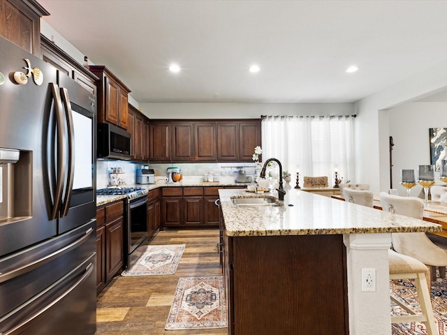 1111 Burlingame Dr, Cleburne, TX 76033 - kitchen featuring stainless steel appliances, a sink, light wood finished floors, an island with sink, and a breakfast bar area