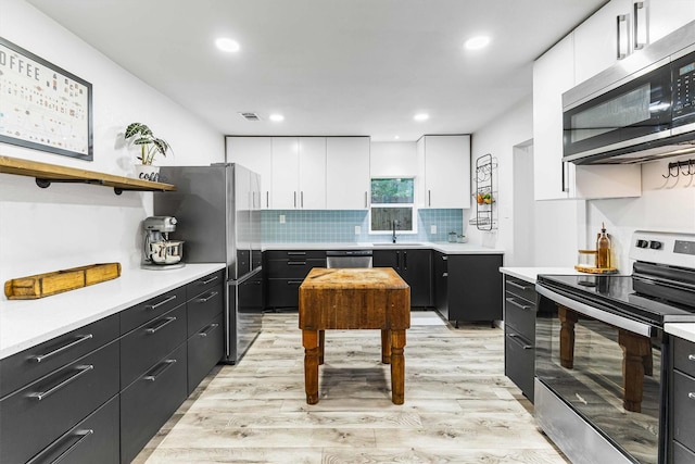 909 N 30th St, Waco, TX 76707 - kitchen with stainless steel appliances, white cabinets, dark cabinets, light countertops, and recessed lighting