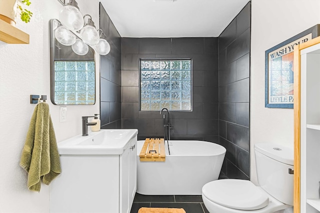 909 N 30th St, Waco, TX 76707 - full bathroom featuring toilet, a freestanding bath, tile patterned floors, vanity, and tile walls