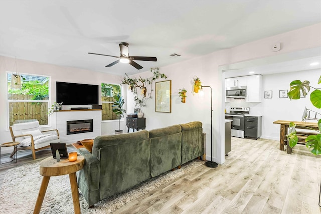 909 N 30th St, Waco, TX 76707 - living area featuring light wood finished floors, a glass covered fireplace, ceiling fan, and baseboards