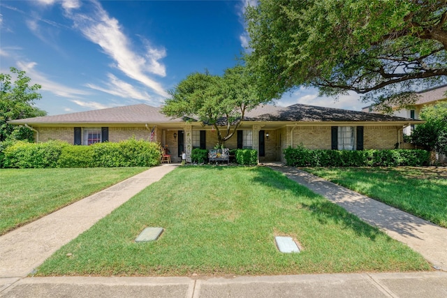ranch-style home with brick siding, a front yard, and covered porch