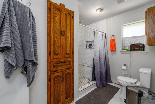 bathroom featuring a tile shower and toilet