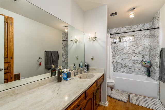 bathroom with toilet, shower / tub combo with curtain, wood finished floors, and vanity