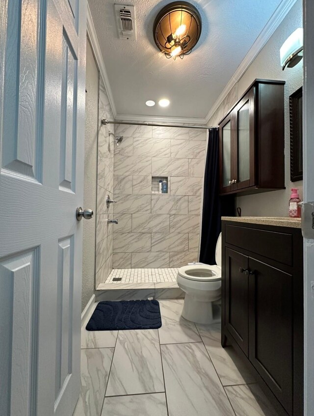 bathroom with marble finish flooring, crown molding, toilet, tiled shower, and vanity