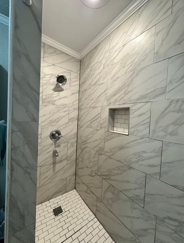 bathroom featuring ornamental molding and tiled shower
