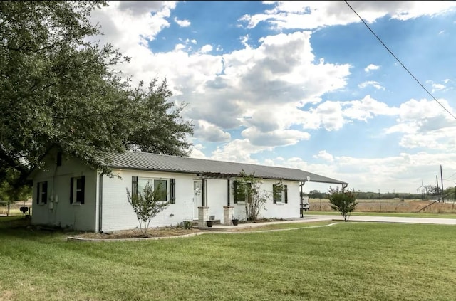 single story home featuring a front yard, metal roof, a carport, and a standing seam roof