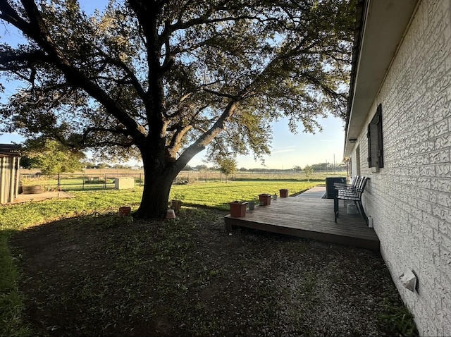 view of yard featuring a wooden deck, a view of countryside, and fence