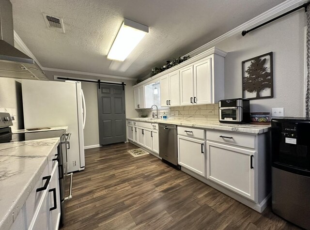 kitchen with stainless steel appliances, a sink, a barn door, white cabinetry, and dark wood-style floors