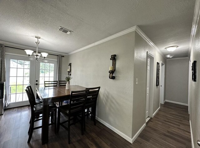 dining room featuring a textured ceiling, a chandelier, dark wood finished floors, ornamental molding, and a textured wall