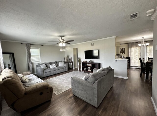 living room with a textured ceiling, a chandelier, dark wood-type flooring, crown molding, and a ceiling fan