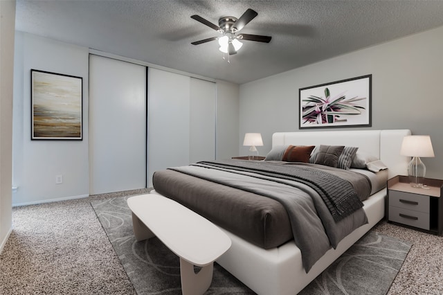 bedroom featuring a closet, a textured ceiling, carpet, baseboards, and ceiling fan