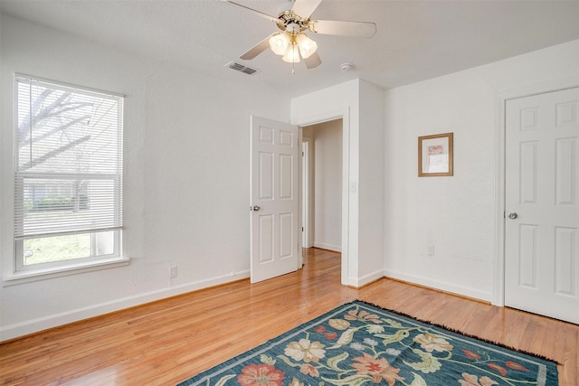 unfurnished bedroom featuring wood finished floors, baseboards, and a ceiling fan