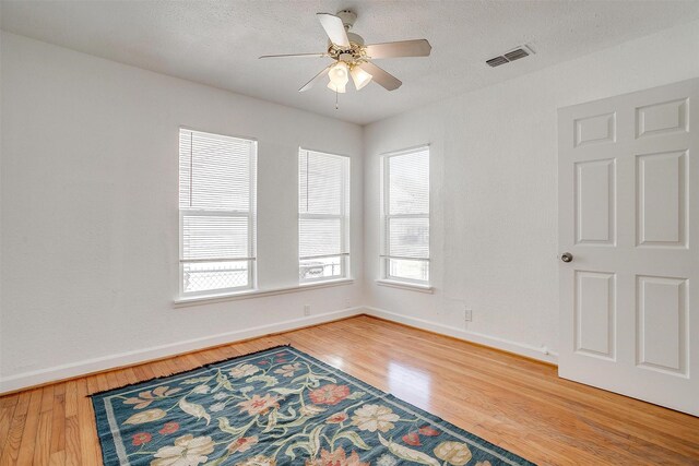 empty room with baseboards, wood finished floors, and a ceiling fan