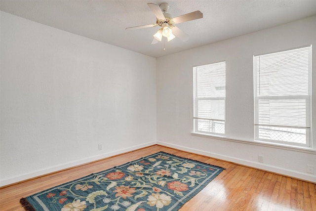 empty room featuring baseboards, wood-type flooring, and ceiling fan