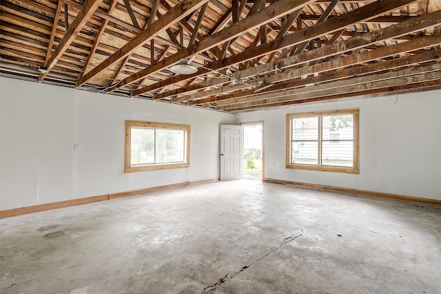 unfurnished room featuring concrete floors, healthy amount of natural light, and baseboards