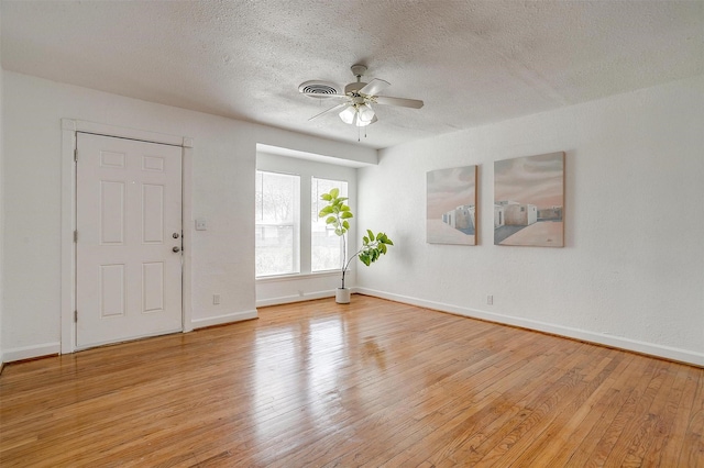 unfurnished room featuring ceiling fan, light wood-type flooring, a textured ceiling, and baseboards