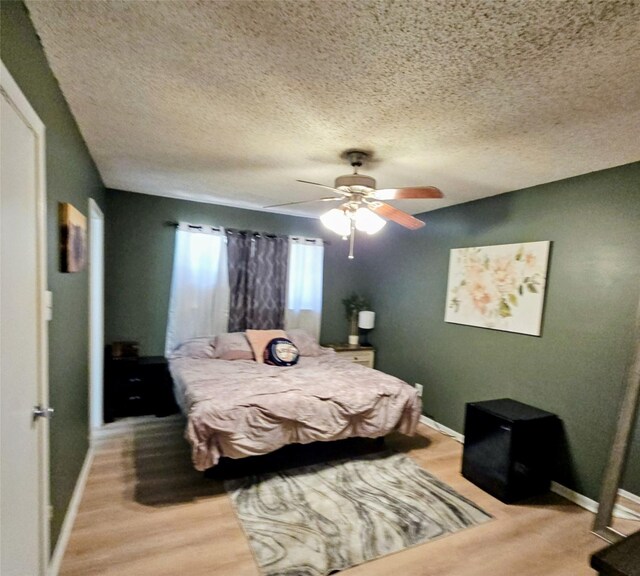 bedroom featuring light wood-style floors, baseboards, a textured ceiling, and ceiling fan