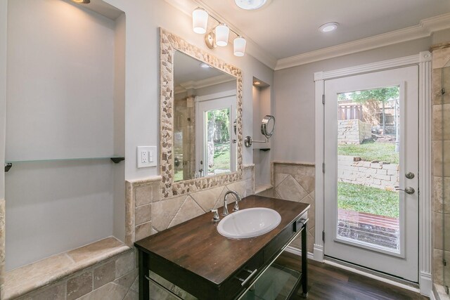 bathroom with ornamental molding, plenty of natural light, tile walls, vanity, and wood finished floors