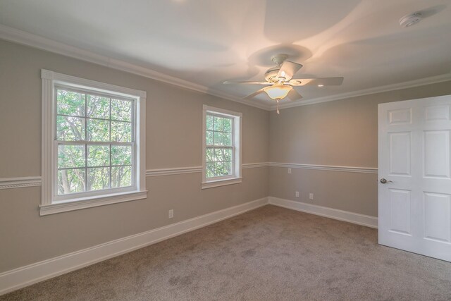 empty room with a smoke detector, carpet floors, ornamental molding, baseboards, and ceiling fan
