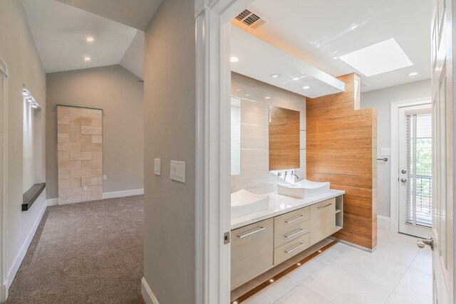 full bathroom featuring a skylight, double vanity, baseboards, tile patterned floors, and recessed lighting